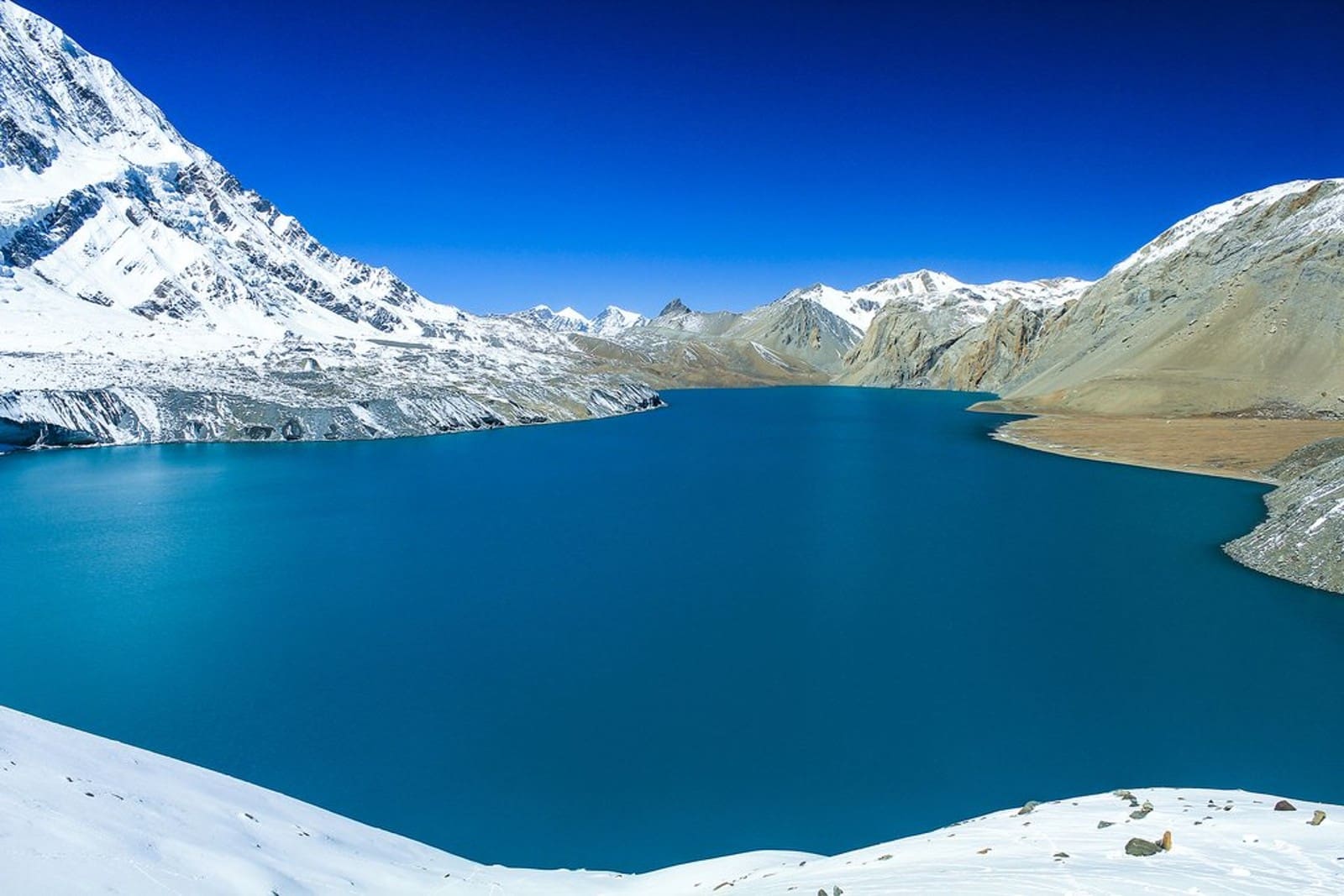 Majestic Snow-Capped Peaks and Serene Blue Waters at Tilicho Lake on the Annapurna Circuit